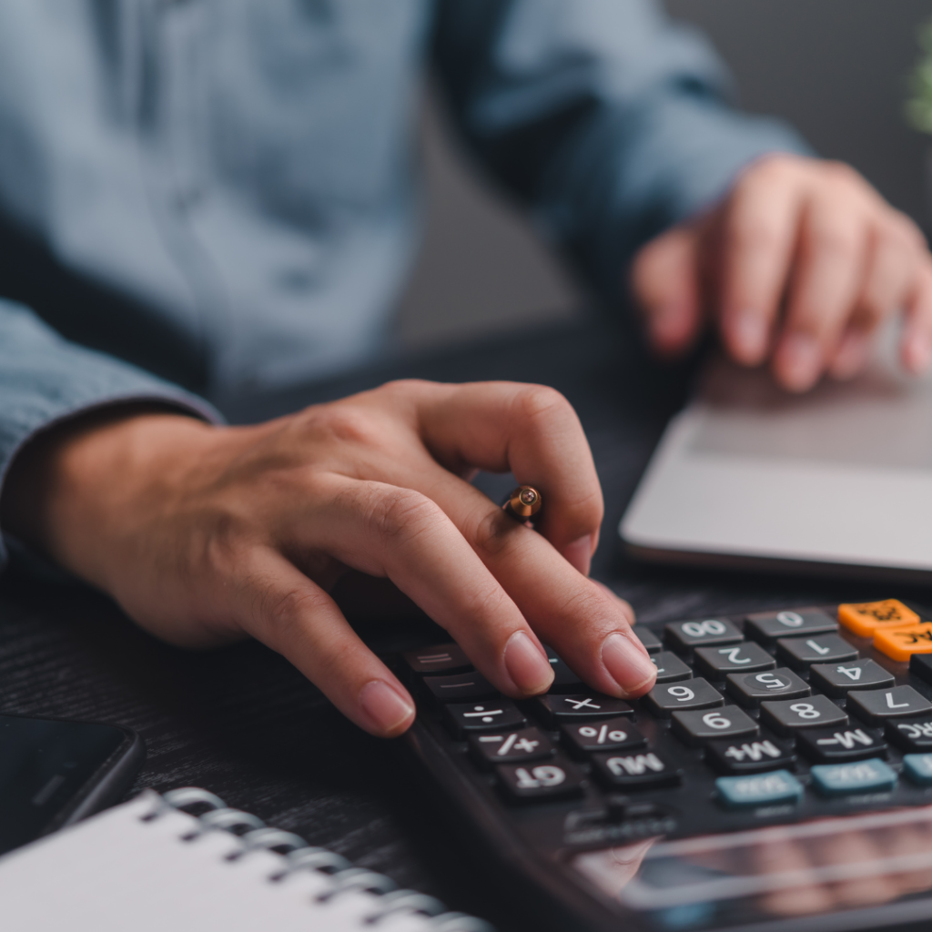 Pessoa calculando honorários advocatícios com calculadora e notebook sobre a mesa.