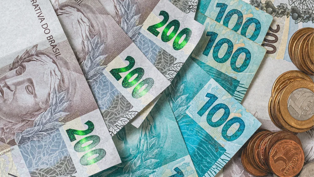 Notas de R$200 e R$100 e moedas representando o teto de 150 salários mínimos no crédito trabalhista