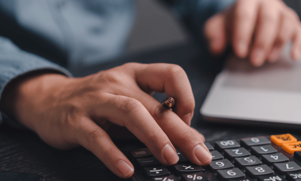 Cálculo de honorários advocatícios em ambiente de trabalho Pessoa calculando honorários advocatícios com calculadora e notebook sobre a mesa.