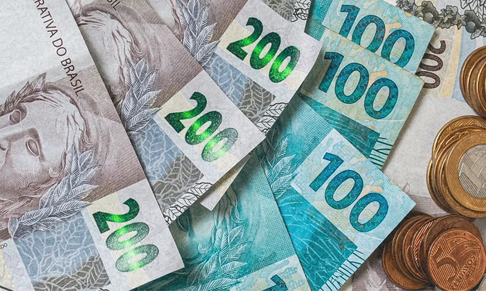 Notas de R$200 e R$100 e moedas representando o teto de 150 salários mínimos no crédito trabalhista